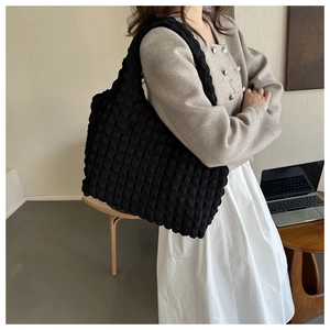 Détail macro du tissu plissé noir d'un grand sac à bandoulière au design épuré