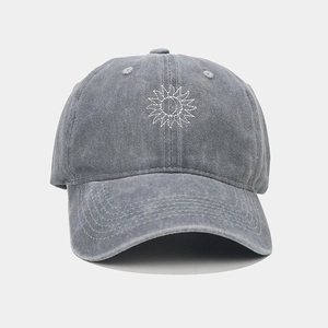 Macro detail of sun and moon embroidery on a washed dark gray cotton baseball cap