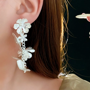 Détail de boucles d'oreilles fleur à pampilles en argent avec breloques et chaînes longues