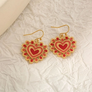 Vue détaillée de boucles d'oreilles cœur rouge avec crochets dorés et bords dentelés