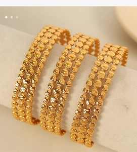 Close-up of three gold titanium bracelets with hammer texture on a jewelry stand