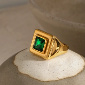 Close-up of vintage gold ring featuring a square emerald green gemstone in a chunky setting