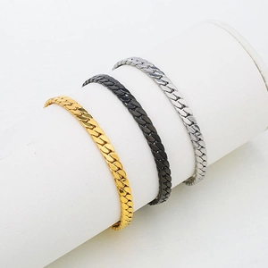 Polished titanium steel Cuban link bracelets in gold, silver, and black on a display