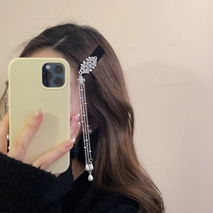 Detail of velvet pearl fringe hair clip with silver tassels on long brunette wavy hair
