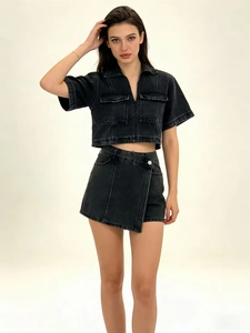 Detailed view of women's black washed denim two-piece set with cropped shirt and asymmetric skirt