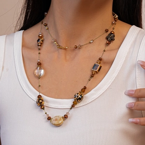 Detail of bohemian glass ceramic beaded necklace with amber and brown beads on a model