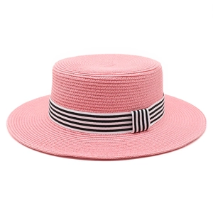 Detail of pink woven straw boater hat featuring a black and white striped ribbon band
