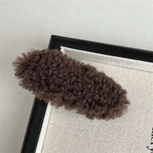 Detailed close-up of dark brown plush faux fur hair clip with soft fuzzy texture