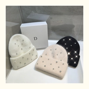 Detailed close-up of chunky knit beanies featuring sparkling rhinestones and plush fur texture