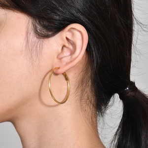 Close-up of large gold hoop earrings on a model showing polished metallic texture