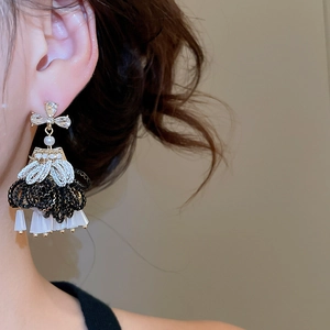 Close-up of dangling black and white tassel earrings with rhinestone bow on female ear