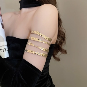 Close-up of hammered gold multi-layer armlet cuff on arm with hollow wavy design