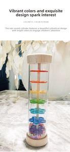 Detail view of transparent rainmaker toy with colorful beads and wooden ends on marble