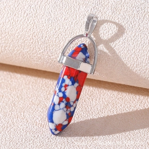 Macro shot of tricolor hexagonal stone pendant with silver metal bail on beige surface
