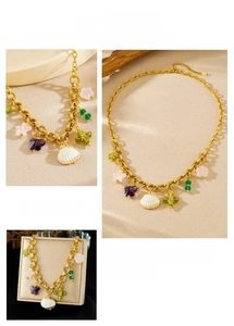 Détail d'un collier chaîne doré avec breloques colorées en forme de coquillage et papillon