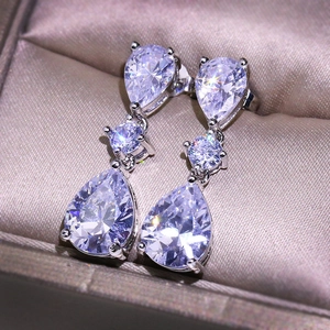 Elegant water drop zircon drop earrings in silver finish on champagne silk background