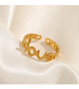 Detail view of gold adjustable LOVE ring on silk background with elegant metallic finish