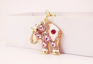 Macro shot of gold elephant keychain with pink crystals and white enamel details