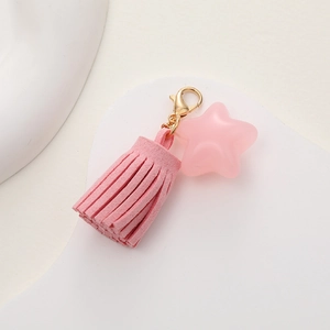 Detailed view of pink suede tassel keychain with translucent star charm and gold lobster clasp