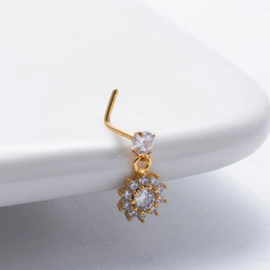 Detailed view of a gold flower pendant nose stud with sparkling clear zircon on a stand