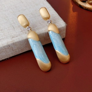Dettaglio di orecchini vintage dorati con resina marmo blu chiaro e cristalli