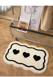 Detail of soft cream-colored bath mat with black heart patterns on wooden floor