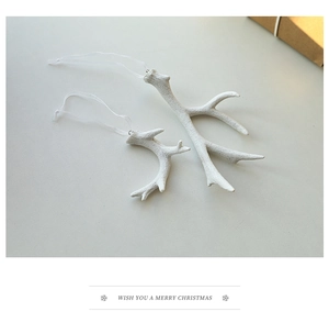 Close-up of elegant white resin reindeer antler ornaments on a festive cream background