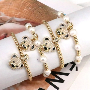 Elegant bear pendant bracelet featuring white pearls and golden metallic beads