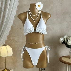 Detailed close-up of white ruffled bikini with halter neck and side-tie high-cut bottoms