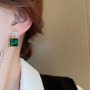 Close-up of model wearing green crystal square stud earrings with gold plating