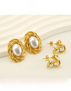 Detail of 18K gold-plated titanium steel earrings with irregular pearls on a white display