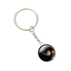 Silver solar system keychain with luminous Saturn glass pendant on white background