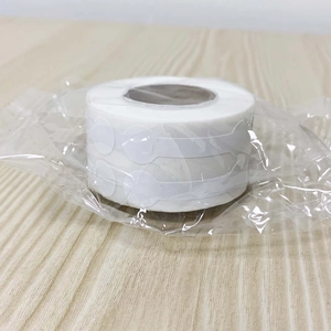 Macro view of white self-adhesive round labels in a roll on light wood background
