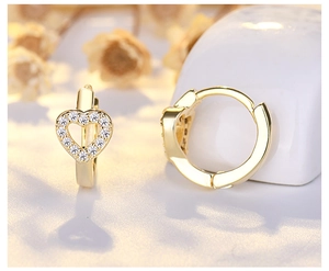 Macro shot of gold-plated hollow heart huggie earrings with pavé set cubic zirconia