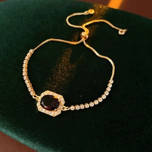 Macro detail of gold adjustable bracelet with purple gemstone on green velvet box
