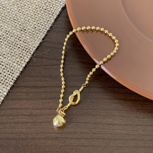 Close-up of a golden beaded S925 sterling silver bracelet with a knot and sphere charm
