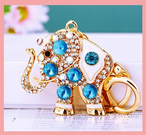 Macro shot of a gold elephant keychain with blue crystals and white enamel details