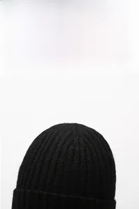 Detail of black rib-knit winter beanie with thick texture and warm folded cuff design