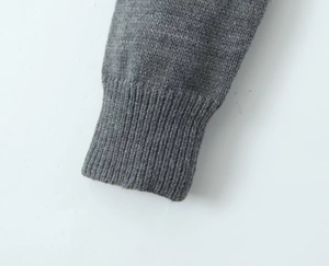 Gros plan sur les poignets en maille côtelée gris foncé montrant la texture du tissu