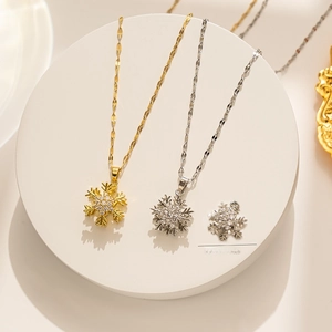 Close-up of rotating snowflake pendants in gold and silver with micro-pave crystals
