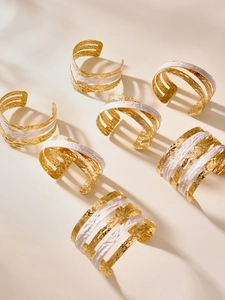 Détail de bracelets manchettes multicouches plaqués or 18 carats avec texture martelée et émail