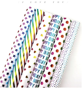 Close-up of 6 iridescent wrapping paper rolls with star, stripe, and heart laser patterns