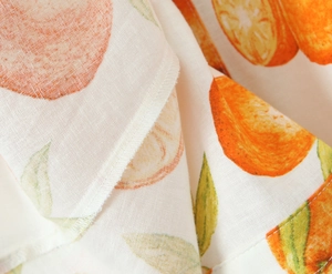 Detail von Leinenkleid-Stoff mit lebhaftem Orangendruck und präziser Nahtqualität