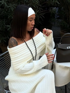 Detailed knit texture of white off-the-shoulder long sleeve dress on elegant outdoor setting