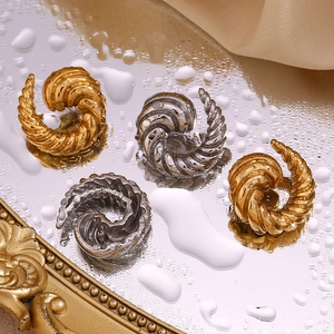 Detailed view of twist-patterned earrings in 18K gold and silver on reflective surface