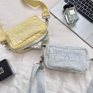 Detail of embroidered bows on mini quilted crossbody bags in yellow and blue colors