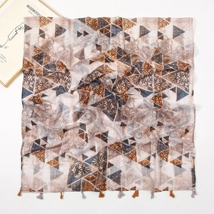 Detail of printed scarf featuring paisley patterns and delicate fringe edge on white background