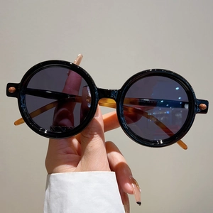 Gros plan de lunettes de soleil rondes noires avec branches ambre et détails de taille