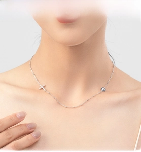 Detail of S925 silver necklace featuring a sparkling diamond cross and evil eye pendant