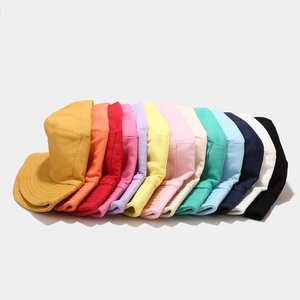 Minimalist double-sided cotton bucket hats in various colors on a grey background